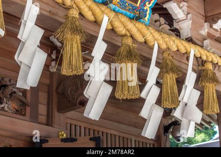 Shimenawa corde e decorazioni in carta a zig-zag (shide) al santuario di Enoshima shinto, Kanagawa, Giappone. Foto Stock