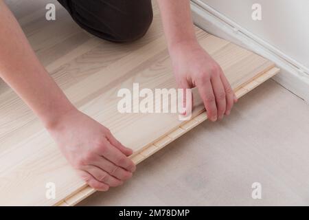 Lavoratore professionista che installa nuovo parquet in interni, primo piano Foto Stock