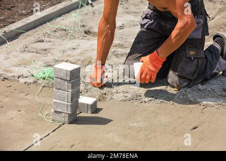 Un operaio installa una corda di nylon per posare le lastre di pavimentazione in una giornata estiva di sole. Spazio di copia. Foto Stock