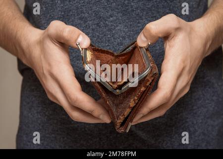 Un portafoglio vuoto nelle mani di un giovane, il concetto di fallimento e crisi finanziaria Foto Stock