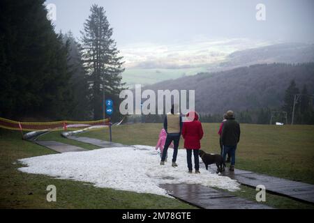 Gersfeld, Germania. 08th Jan, 2023. Un gruppo di persone sta in piedi su un ultimo punto di neve sul Wasserkuppe. La mancanza di neve e le temperature miti impediscono alle stazioni sciistiche di Hesse di godersi le piste. Credit: Sebastian Gollnow/dpa/Alamy Live News Foto Stock