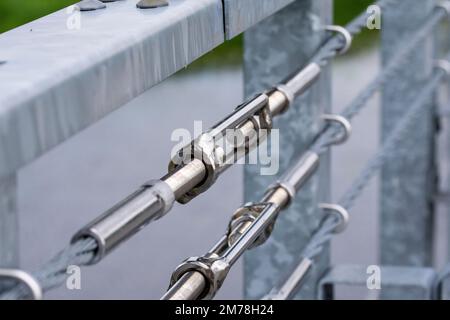 Tenditori che collegano le funi di sicurezza alla ringhiera sul ponte. Estate. Foto Stock