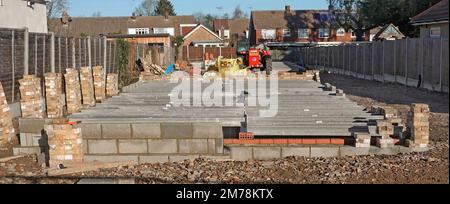 Staccata casa sottostruttura costruzione progresso calcestruzzo prefabbricato piantana travi a forchetta sollevata dal camion su pareti portanti Inghilterra UK Foto Stock