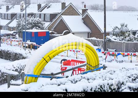 Dicembre nevicate e ghiaccio stop lavori stradali su villaggio sotterraneo progetto di sostituzione delle infrastrutture neve su avvolto giallo tubo principale gas plastica nel Regno Unito Foto Stock