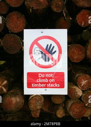 Un cartello nel cortile di legno che consiglia alle persone di non salire sui tronchi Foto Stock