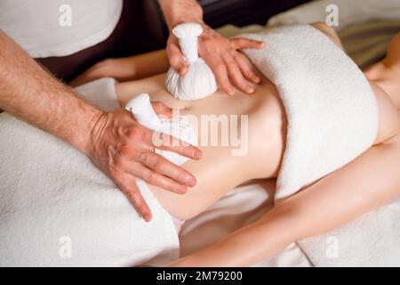 Donna con massaggio addominale con bustine di erbe aromatiche Foto Stock