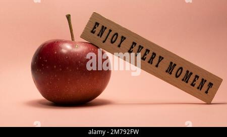 GODETEVI OGNI MOMENTO è scritto sulla superficie di legno. Concetto di legno. Foto Stock