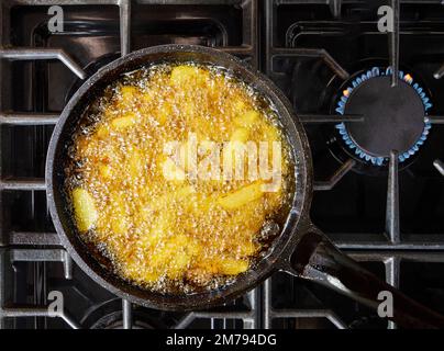 Patatine fritte friggendo in una padella. Le patatine fritte sono patate fritte. Foto Stock