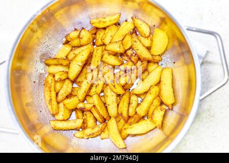 Patatine fritte scolando il grasso in eccesso, dopo la frittura, in un setaccio. Foto Stock