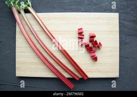 Rinfresco su tagliere in legno su sfondo nero, vista dall'alto. Processo di preparazione. Foto Stock