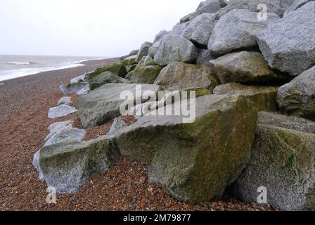 35 metri Granite Boulder Rock Revetment Flood Defence, bagnata dall'acqua di mare con alghe verdi, sommersa in ciottoli. Thorpeness Beach 31st dicembre 2022 Foto Stock