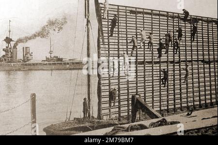 Circa 1930 - uomini che erigono un obiettivo per navi da guerra Navali (HMS Nelson in background). Foto Stock