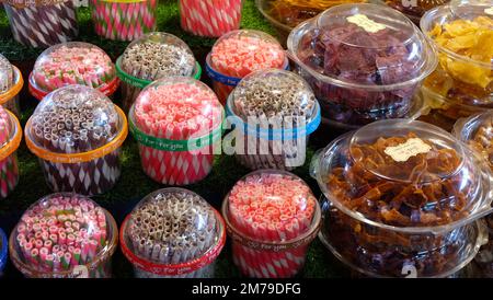 Rotoli di wafer colorati confezionati in contenitori trasparenti, esposti ordinatamente accanto ad altri spuntini, in un negozio di articoli. Foto Stock