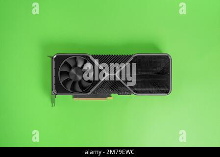 Scheda grafica moderna su superficie verde. Radiatore massiccio con due refrigeratori. Moderna scheda grafica per videogame e rendering. Vista dall'alto, disposizione piatta Foto Stock