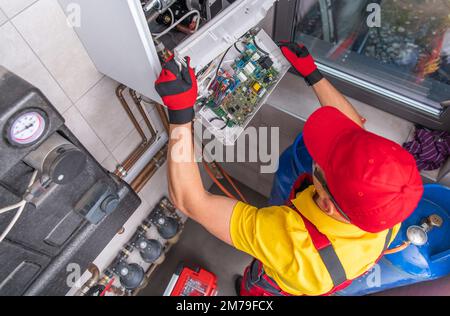 Riparazione professionale di idraulici caucasici riscaldatore dell'acqua a gas rotto. Manutenzione dell'impianto di riscaldamento residenziale. Vista dall'alto. Foto Stock