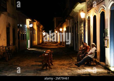 Un bellissimo scatto di persone sedute in una strada illuminata a Paraty, Brasile Foto Stock