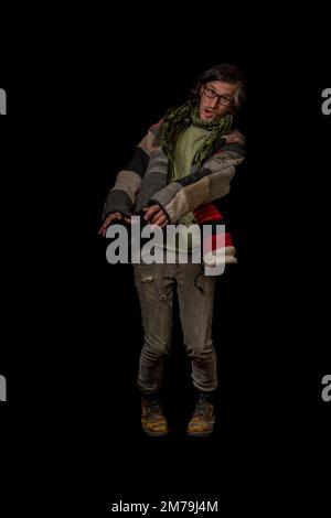 Uomo con pullover in lana colorata e pantaloni grigi con grandi stivali gialli e fondo nero Foto Stock