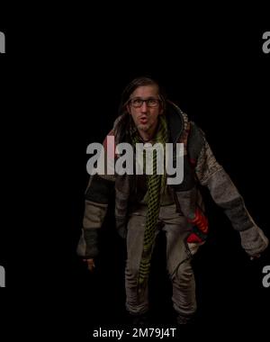 Uomo con pullover in lana colorata e pantaloni grigi con grandi stivali gialli e fondo nero Foto Stock