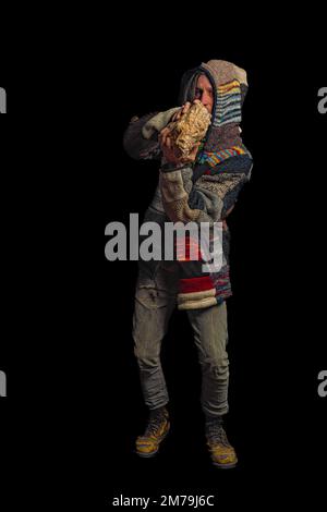 Uomo con pullover in lana colorata e pantaloni grigi con grandi stivali gialli e fondo nero Foto Stock