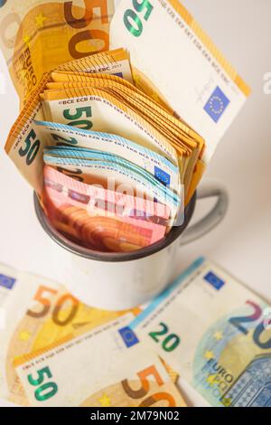 Banconote in euro in tazza bianca con fondo bianco e spazio copia Foto Stock