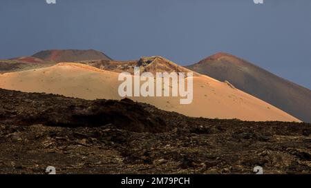 Parco Nazionale di Timanfaya, montagne di fuoco, paesaggio vulcanico nero, collina di lava ocra, collina di lava bruna rossastra, cielo scuro paesaggio volcanico, Lanzarote Foto Stock