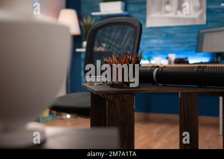 Primo piano di matite da colorare giare sopra la scrivania con forniture artistiche nella stanza vuota dello studente d'arte. Contenitori colorati di penne posti sul tavolo di lavoro dell'artista di disegno all'interno di uno studio di artigianato vuoto. Foto Stock