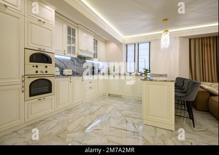 Cucina classica color crema con isola che serve come zona pranzo in appartamento monolocale Foto Stock