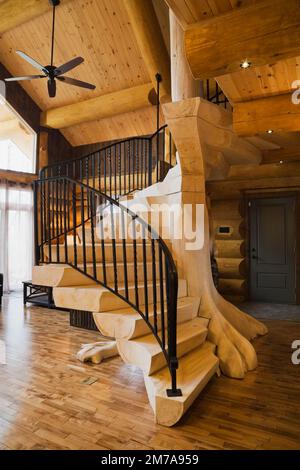 Scale in legno sbiancate con ringhiere in ferro battuto nero nel soggiorno all'interno di una lussuosa casa di legno. Foto Stock