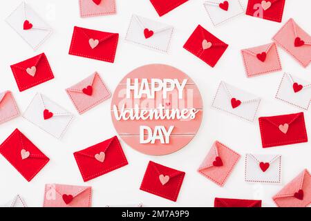Buon messaggio di San Valentino e molte buste felt con cuori su sfondo bianco, vista dall'alto Foto Stock