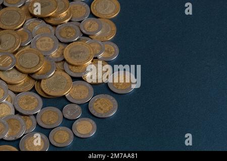 pila di monete messicane in pesos, su una superficie blu, con spazio copia. Foto Stock
