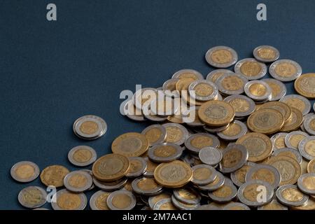 pila di monete messicane in pesos, su una superficie blu, con spazio copia. Foto Stock