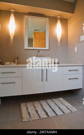 Lavabo con ciotola in porcellana bianca e lavandino laccato, specchio nel bagno degli ospiti al piano superiore all'interno di una casa moderna in stile cubista. Foto Stock