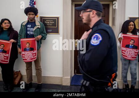 Washington, Stati Uniti d'America. 06th Jan, 2023. Un ufficiale della polizia del Campidoglio degli Stati Uniti passa davanti ai manifestanti dei cittadini finali Uniti mentre si trovano fuori dall'ufficio del rappresentante eletto degli Stati Uniti George Santos (repubblicano di New York) nel Longworth House Building a Washington, DC, venerdì 6 gennaio 2023. Non ci sono stati arresti e il signor Santos ha evitato di andare al suo ufficio. Credito: Rod Lammey/CNP/Sipa USA (RESTRIZIONE: NON sono disponibili quotidiani o quotidiani di New York o New Jersey entro un raggio di 75 km da New York City) credito: Sipa USA/Alamy Live News Foto Stock