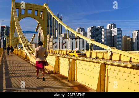 Una donna adulta cammina per lavorare attraverso il ponte Roberto Clemente a Pittsburgh Foto Stock