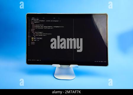 Scrittura del codice del computer visualizzato su sfondo azzurro del monitor Foto Stock