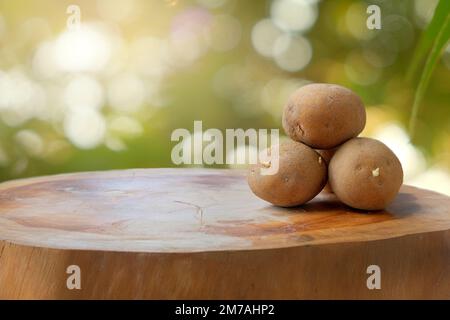 Patate germogliate su un tavolo di legno con sfondo sfocato e luce solare Foto Stock