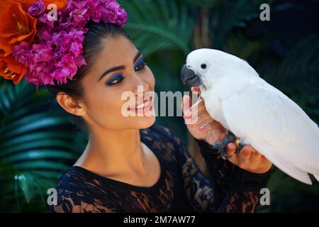 Il mio prezioso. una donna esotica con un pappagallo appollaiato sulla sua mano. Foto Stock