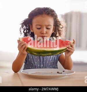 Questo è più grande di me. una bambina carina che mangia anguria. Foto Stock