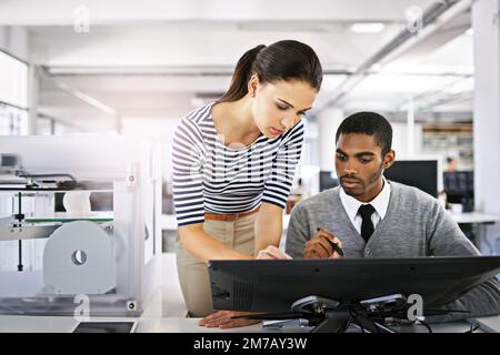 Lavorare alla progettazione 3D. due colleghi che parlano insieme su un computer touchscreen mentre lavorano con una stampante 3d. Foto Stock