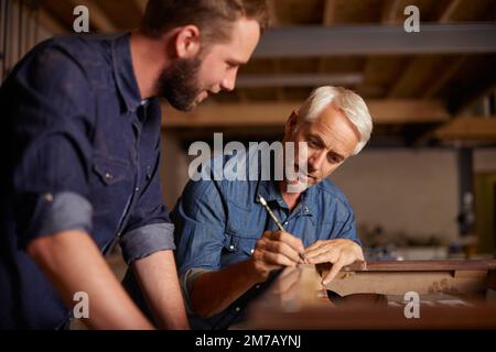 Fare del fai da te con papà. un padre e un figlio che lavorano insieme per un progetto di carpenteria in un'officina. Foto Stock