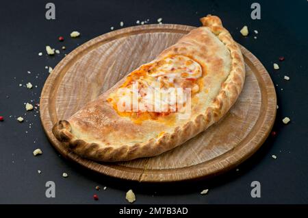 Tradizionale cibo georgiano khachapuri sul piatto di legno su sfondo nero Foto Stock