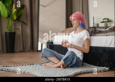 Tranquilla ragazza a piedi nudi meditando sul pavimento della camera da letto Foto Stock