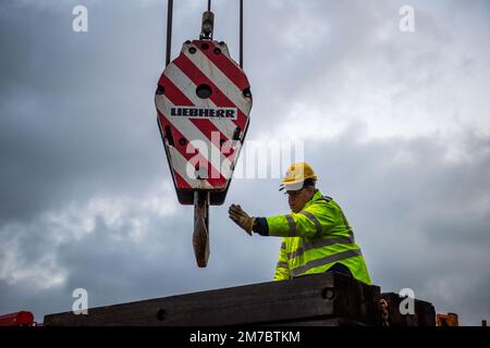 09 gennaio 2023, Renania settentrionale-Vestfalia, Minden: Un dipendente della società di carico pesante dà istruzioni all'operatore della gru. Il carro indiano è sottoposto a diversi test climatici da parte di Deutsche Bahn a Minden. A tal fine, il carro deve essere prima scaricato utilizzando due gru per impieghi gravosi. Foto: Lino Mirgeler/dpa Foto Stock