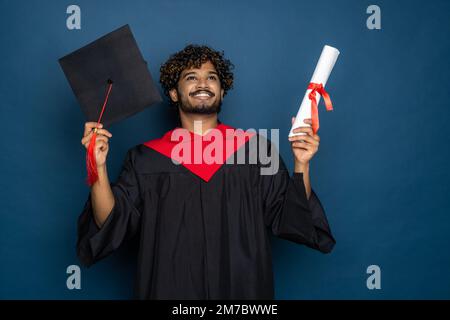 Istruzione, laurea e concetto di persone - felice indiano studente di laurea maschile in Mortarboard e abito da bachelor Foto Stock