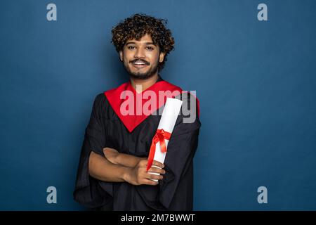 Istruzione, laurea e concetto di persone - felice indiano studente di laurea maschile in Mortarboard e abito da bachelor Foto Stock