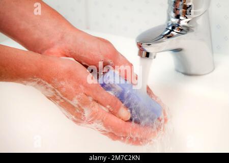 La donna lava le mani sotto acqua corrente e sapone Foto Stock