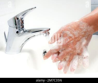 La donna lava le mani sotto acqua corrente e sapone Foto Stock