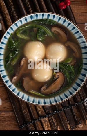 Mangiare il grande tangyuan yuanxiao (tang yuan, palle glutinose di riso gnocchi) con una zuppa saporita in una ciotola per il festival del solstizio d'inverno. Foto Stock