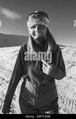 Primo piano donna gioiosa su un ritratto monocromatico innevato di montagna Foto Stock