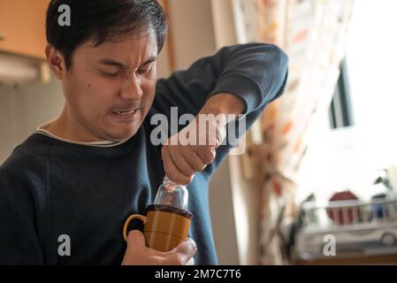 L'uomo tira fuori un biberon bloccato in una tazza o in una tazza. Foto Stock